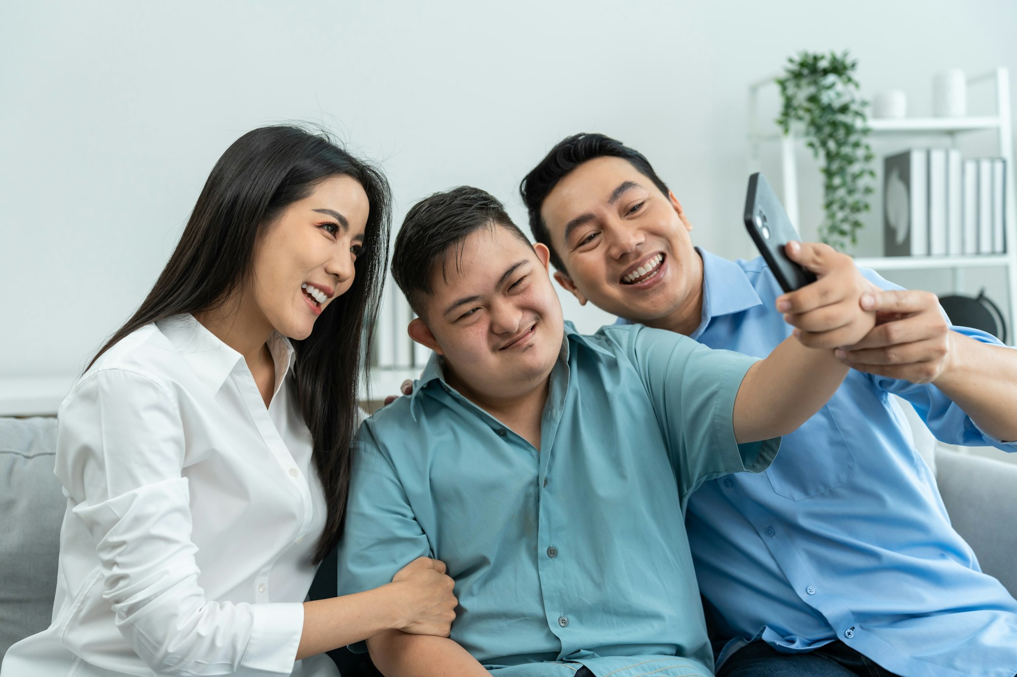 Otizmli oğlu olan aile telefon kullanarak evde selfie çekiyor.